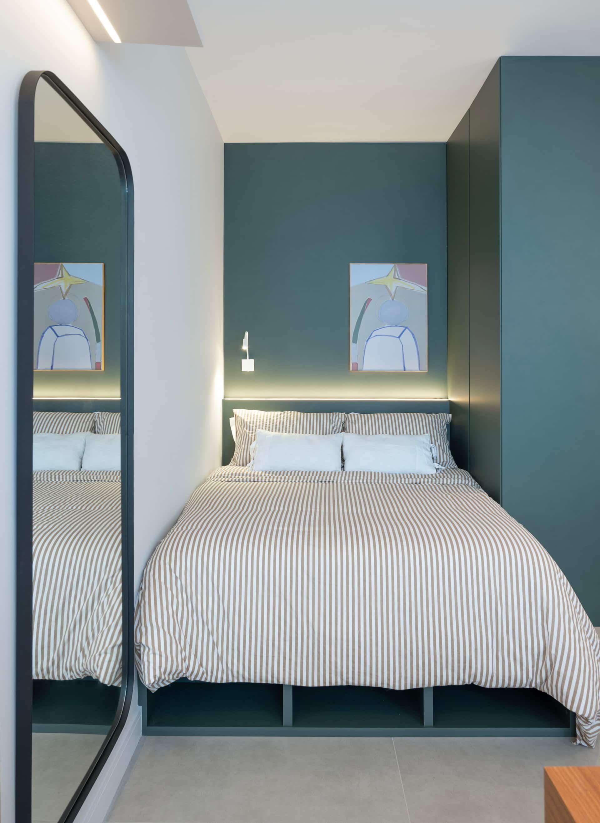 Cama de casal com roupa de cama listrada e parede verde